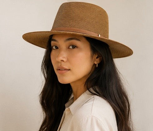 Woman wearing a brown straw hat against a plain background