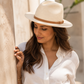 Woman wearing a white hat and white shirt against a neutral background