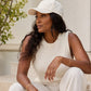 Woman in a white outfit sitting outdoors with a neutral background