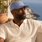 Man wearing a blue cap and white shirt sitting outdoors with scenic background