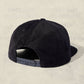 Black cap with textured pattern on a beige background