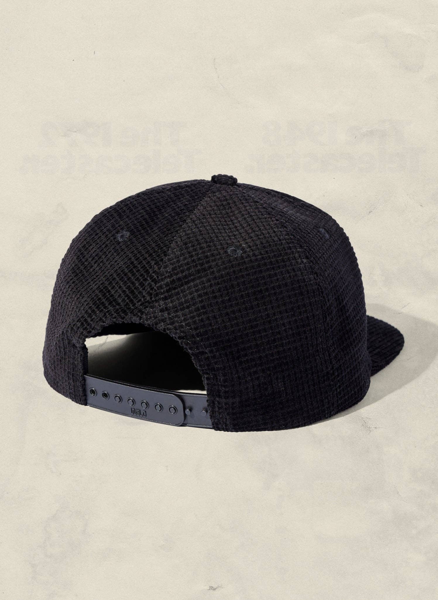 Black cap with textured pattern on a beige background