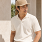 Man wearing a beige cap and white shirt standing outdoors.
