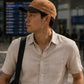 Man wearing a beige cap and light-colored shirt in an airport setting