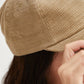 Close-up of a person wearing a beige knit cap with a blurred background