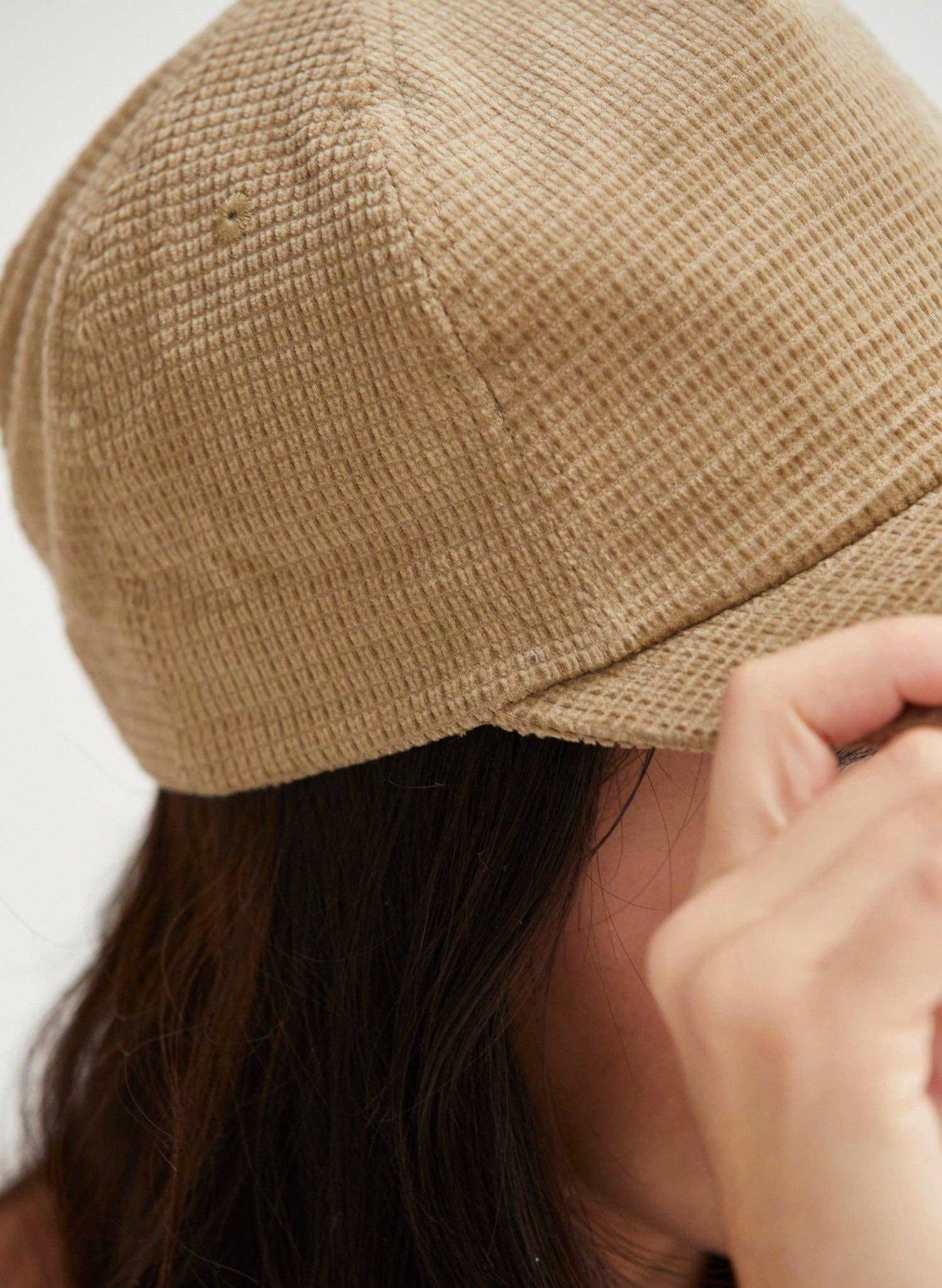 Close-up of a person wearing a beige knit cap with a blurred background