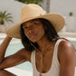 Woman wearing a straw hat and beige top by a poolside