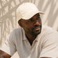 Man wearing a beige cap and shirt against a neutral background
