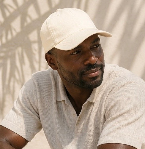 Man wearing a beige cap and shirt against a neutral background