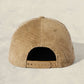 Beige textured cap with a leather strap on a light beige background