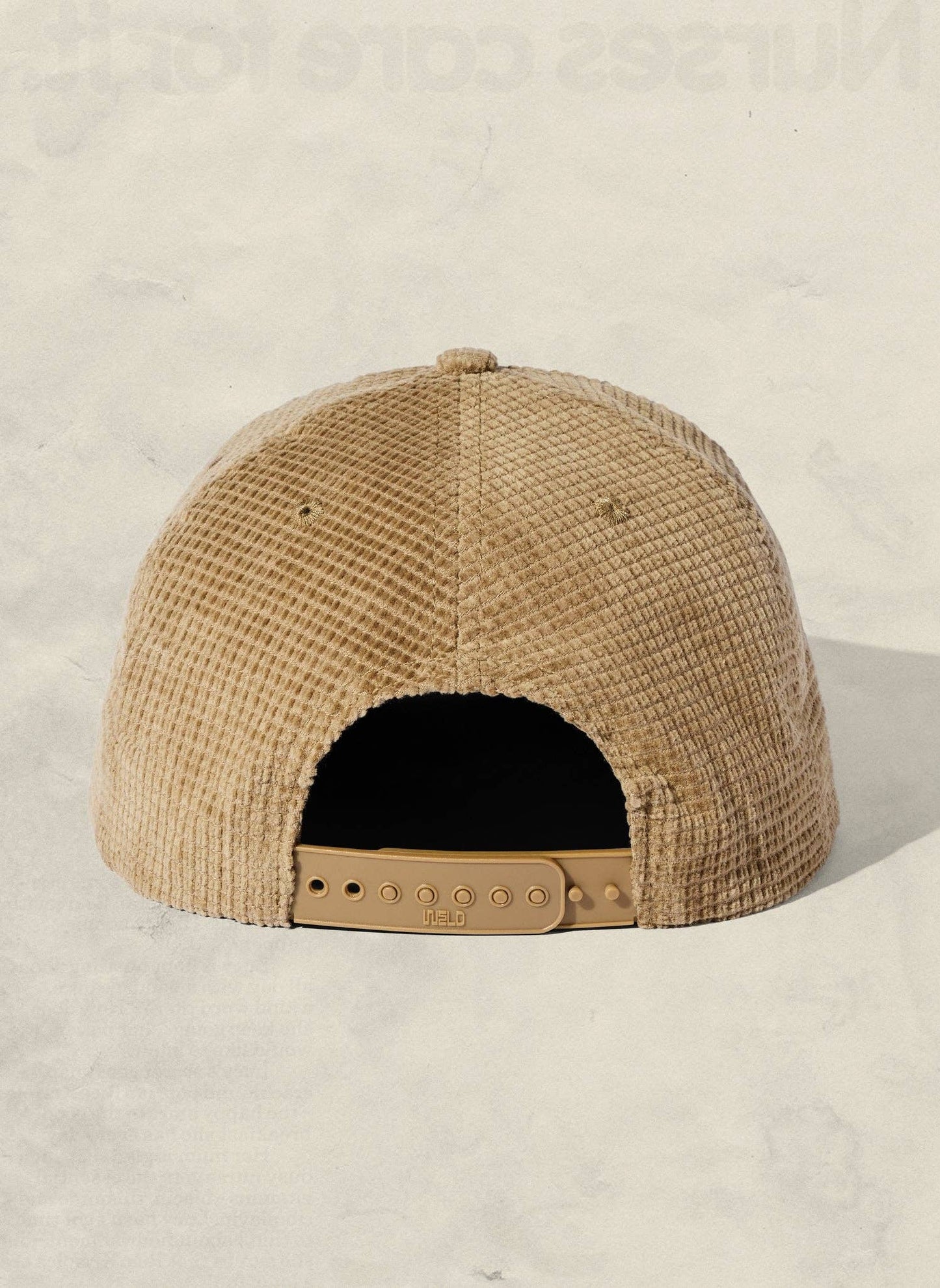 Beige textured cap with a leather strap on a light beige background