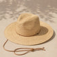 Beige straw hat with a wide brim on a sandy surface