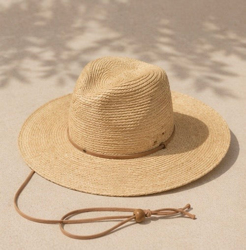 Beige straw hat with a wide brim on a sandy surface