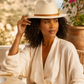 Woman wearing a beige hat and white shirt outdoors with blurred background