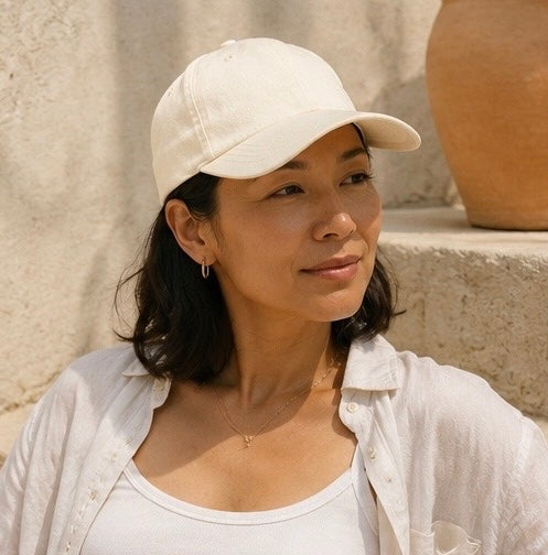 Woman wearing a beige cap and white shirt against a neutral background