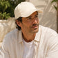 Man wearing a beige cap and light-colored shirt outdoors