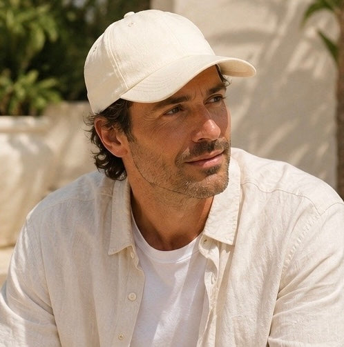 Man wearing a beige cap and light-colored shirt outdoors