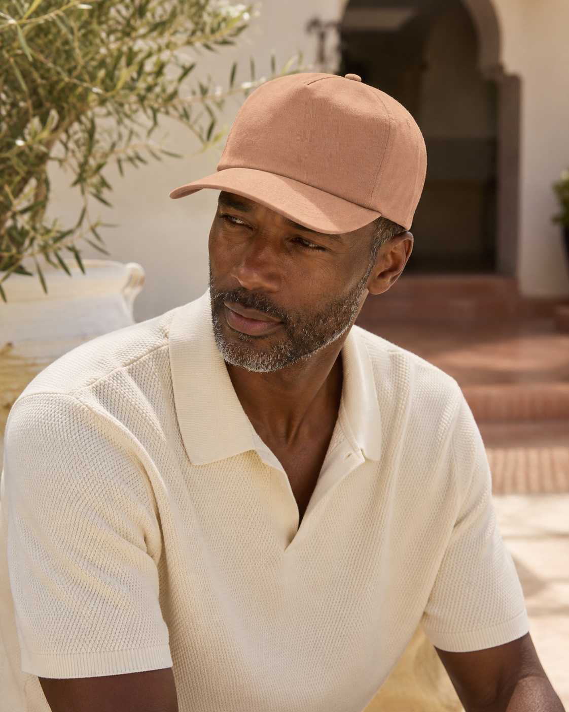 Man wearing a beige cap and polo shirt outdoors