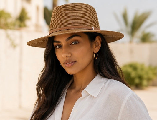 Woman wearing a brown hat and white shirt with a blurred outdoor background