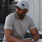 Man wearing a gray cap and light-colored shirt sitting on steps.
