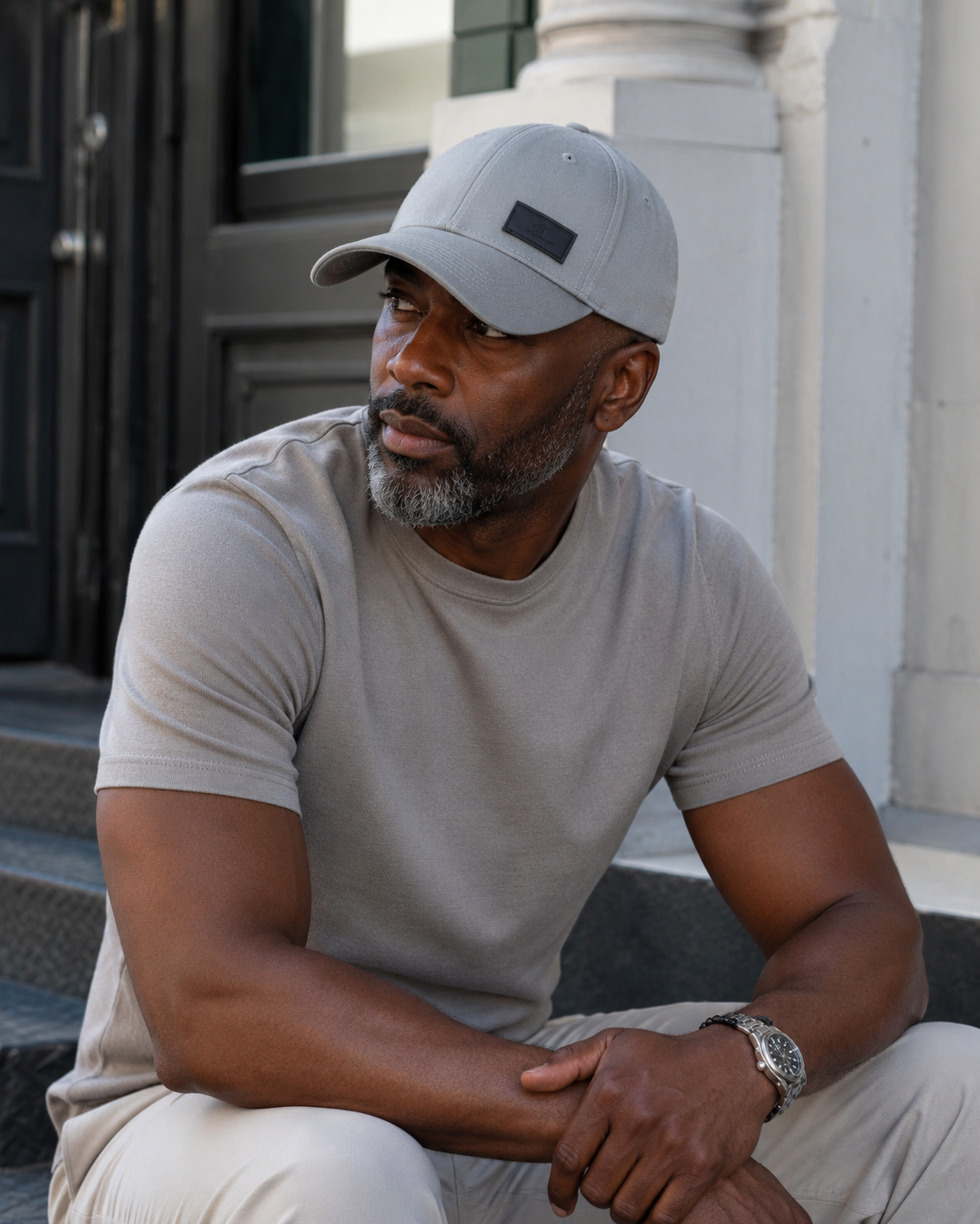 Man wearing a gray cap and light-colored shirt sitting on steps.