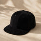 Black textured cap on a beige fabric background