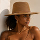 Woman wearing a brown hat and tank top against a neutral wall