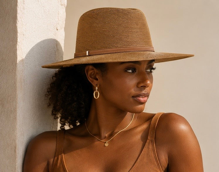 Woman wearing a brown hat and tank top against a neutral wall