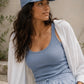 Woman wearing a blue cap, light blue tank top, and matching pants with a white cardigan.