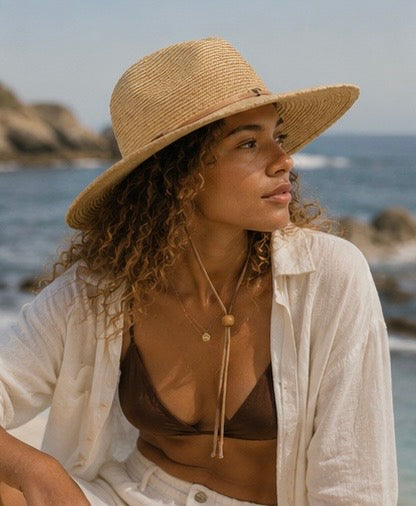 Woman wearing a straw hat and white shirt by the ocean