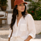 Woman wearing a white outfit and brown cap in an outdoor setting