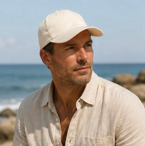 Man wearing a beige cap and light shirt by the ocean