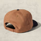 Brown cap with black brim on a beige background