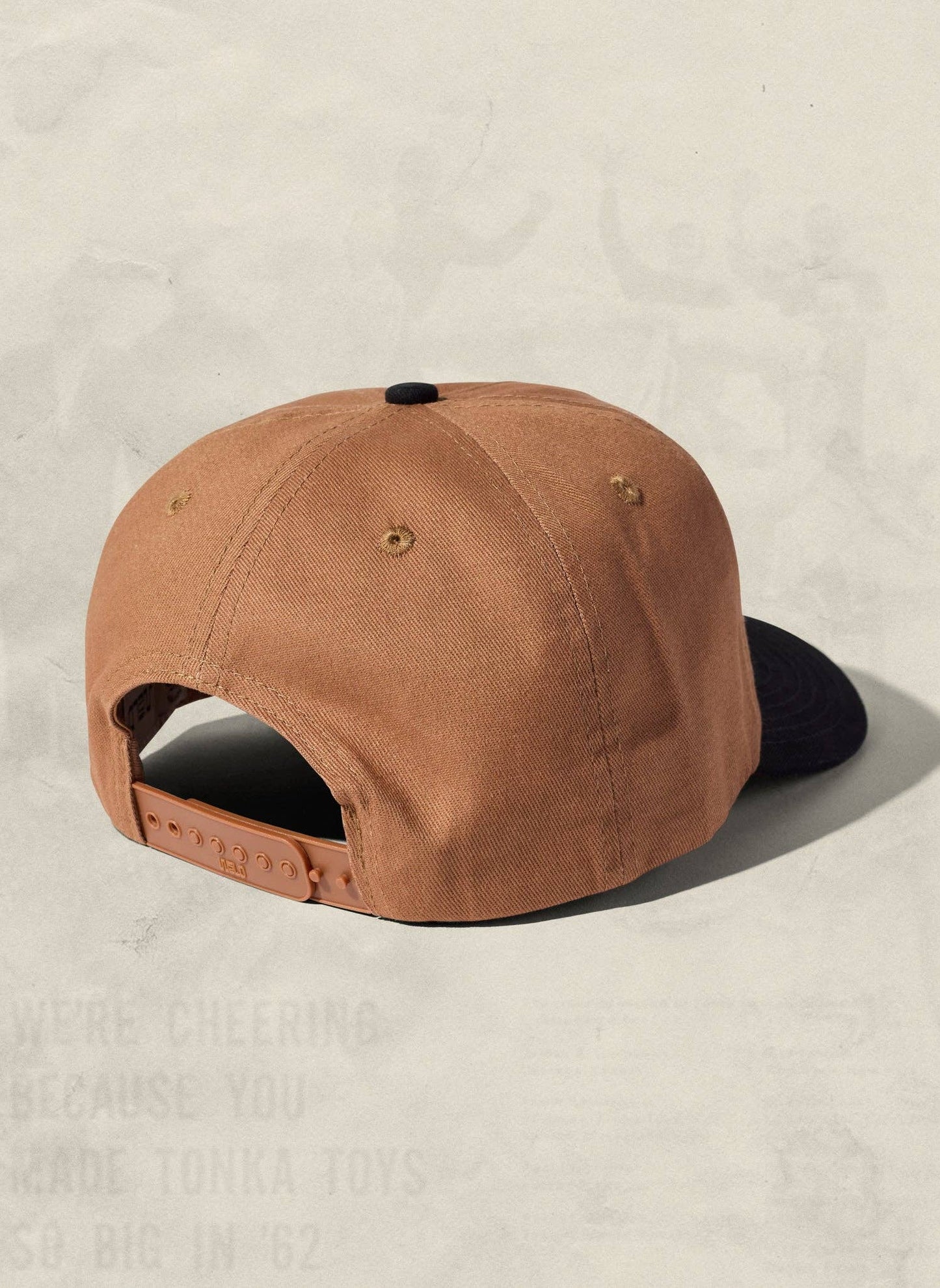 Brown cap with black brim on a beige background